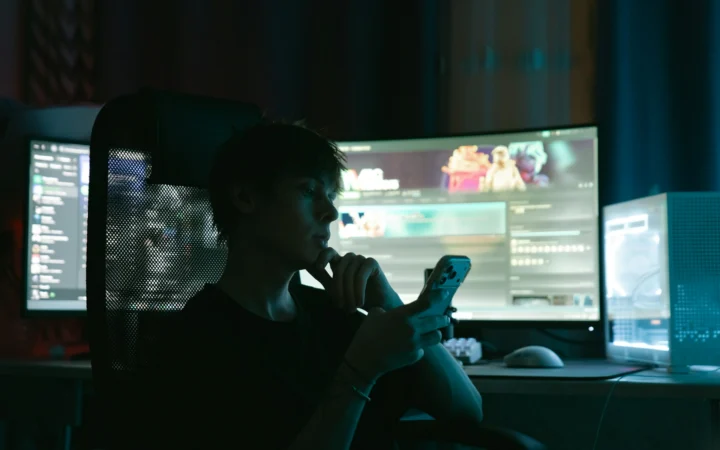 Glowing smartphone game screen in a dark room, illustrating Apple gaming on iPhone