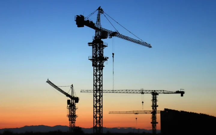 Construction crane silhouetted against a dramatic sunset, symbolising autonomous construction