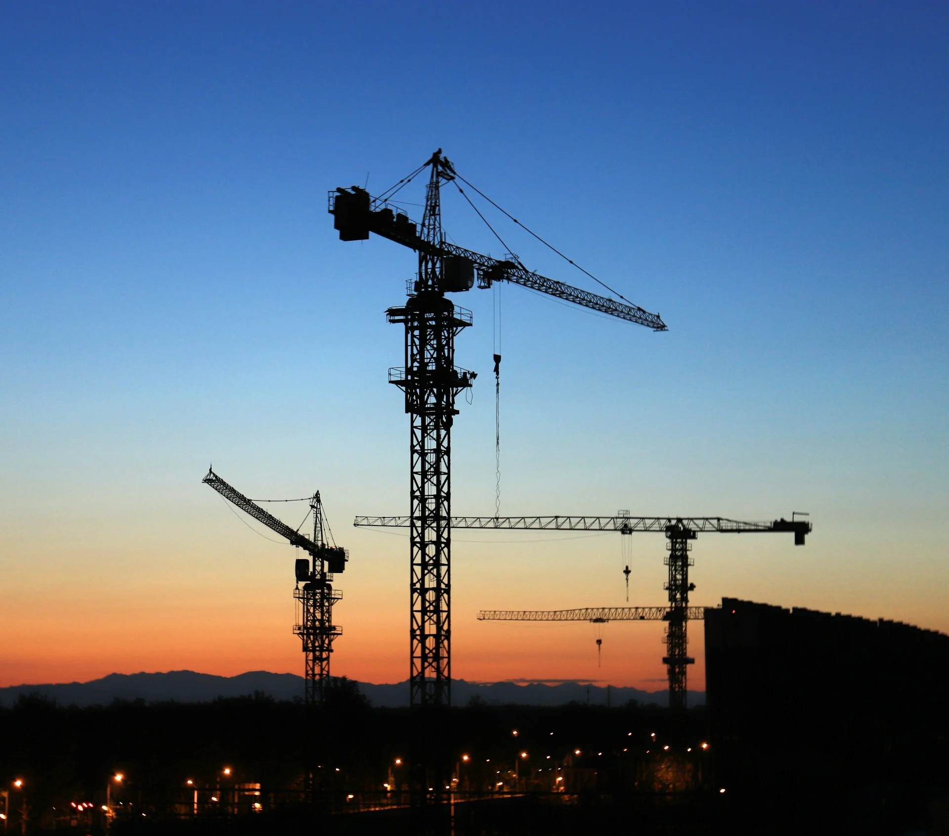 Construction crane silhouetted against a dramatic sunset, symbolising autonomous construction