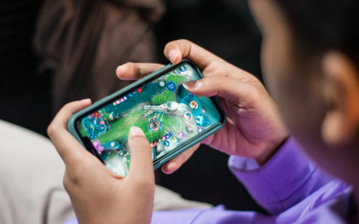 Hands holding a smartphone playing a strategy game, as in Battledrones