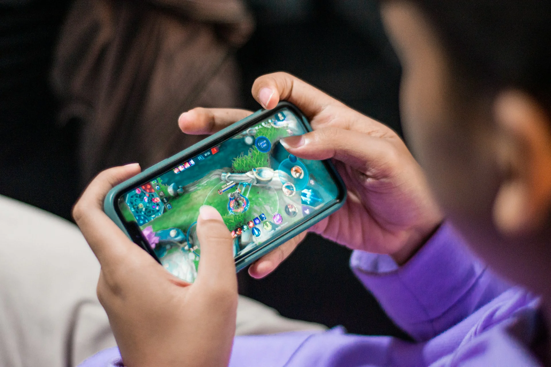 Hands holding a smartphone playing a strategy game, as in Battledrones