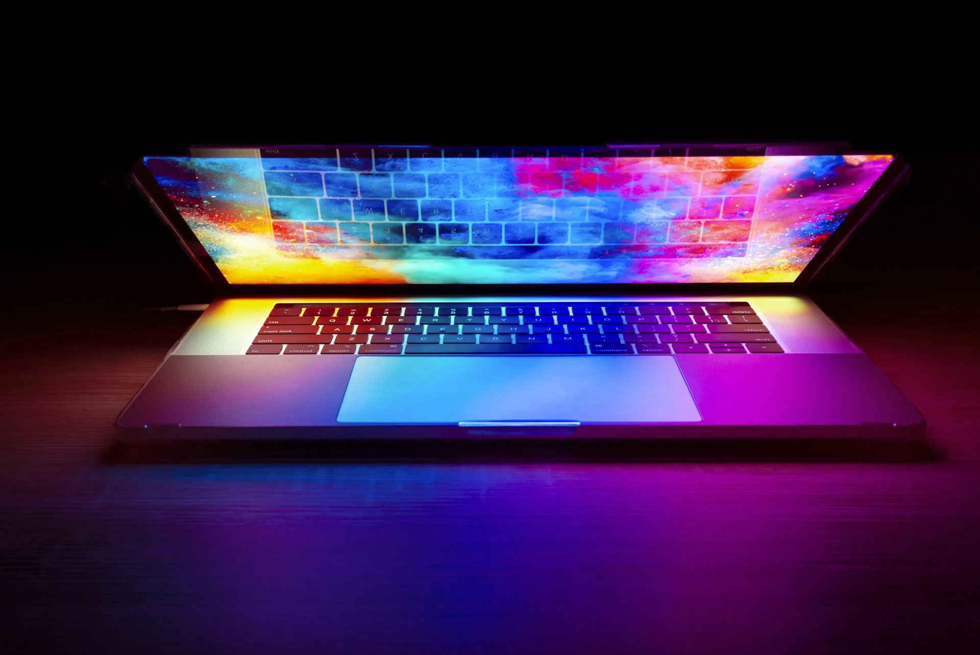 M6 MacBook Pro style laptop glowing in a dark room