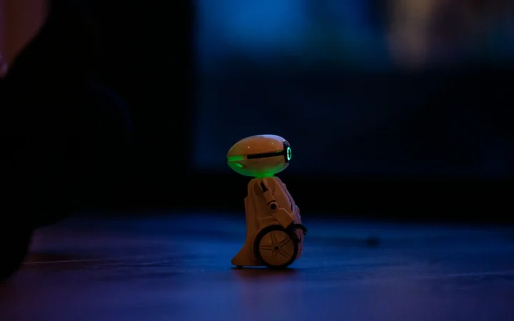 Small walking robot under dramatic light, evoking the Microduck robot duck