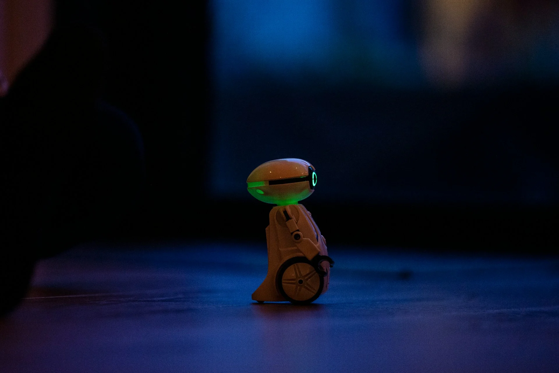 Small walking robot under dramatic light, evoking the Microduck robot duck