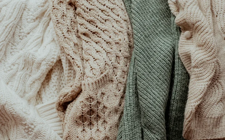 Stack of folded sweaters ready for a seasonal wardrobe swap on a raised working surface
