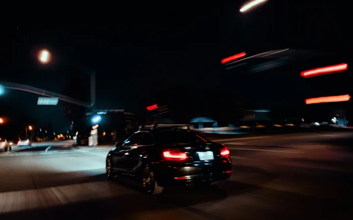 Electric car under dramatic red light, illustrating the fall in Tesla profit