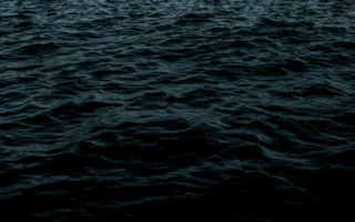 Submarine surfacing in a dark ocean, illustrating UK nuclear submarines at sea