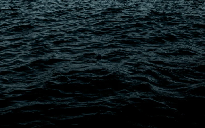 Submarine surfacing in a dark ocean, illustrating UK nuclear submarines at sea